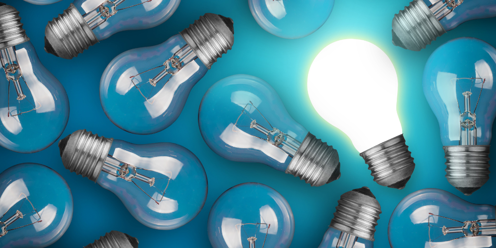 A group of lightbulbs on a blue background. One lighbulb is lit.