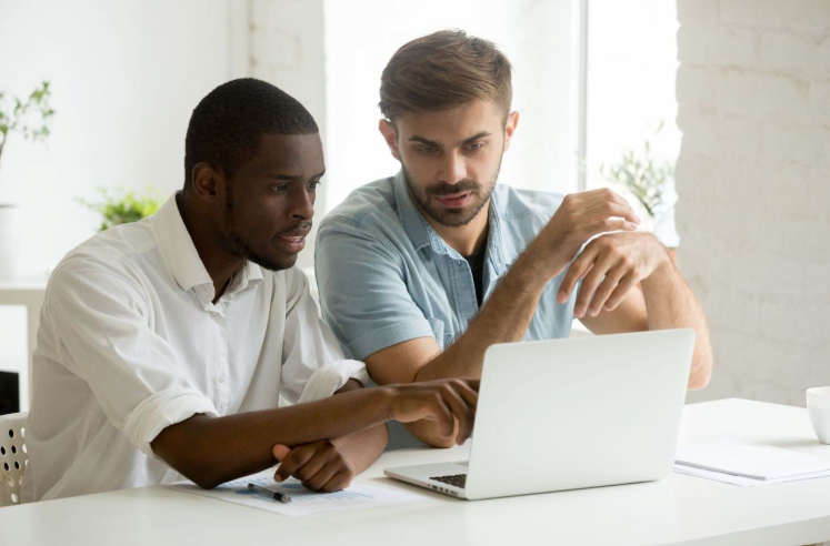 Two men sitting in front of the monitor screen wondering what happened 