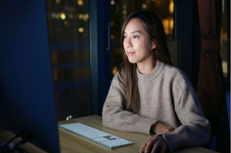 A woman sitting in front of the monitor with a survey options on the screen 