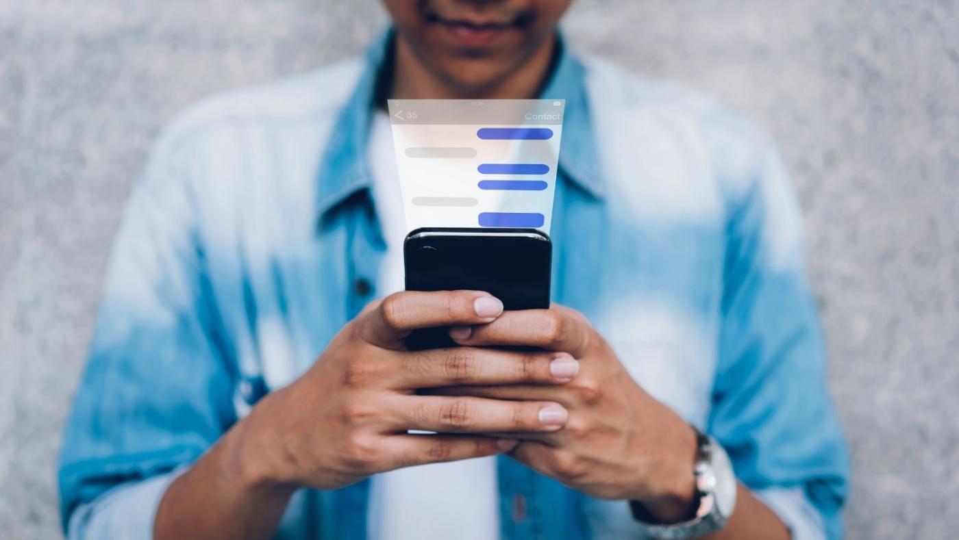 Imagen de una persona mirando una app de mensajería en su celular. 