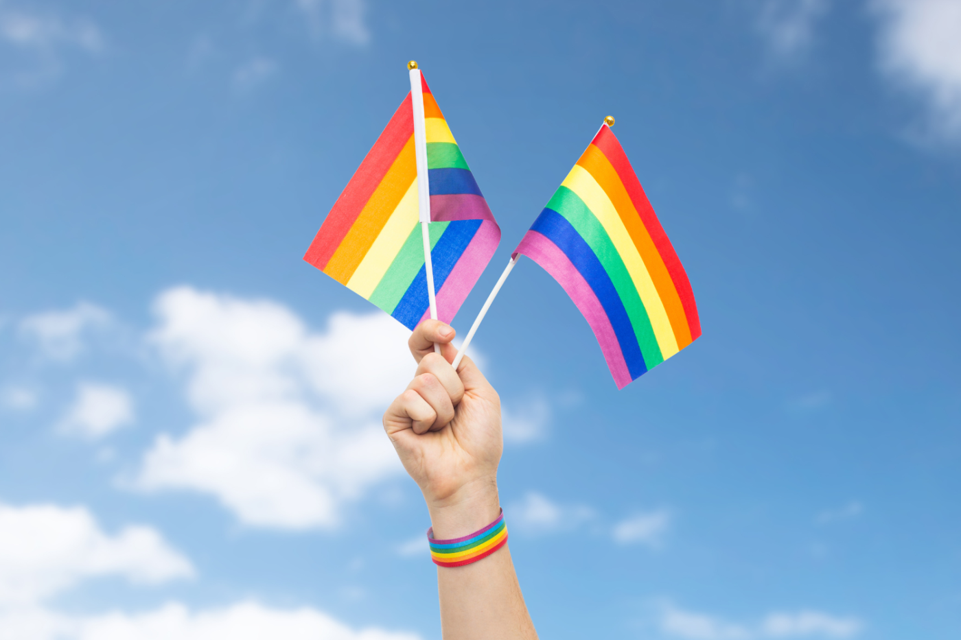a hand holding 2 rainbow flags