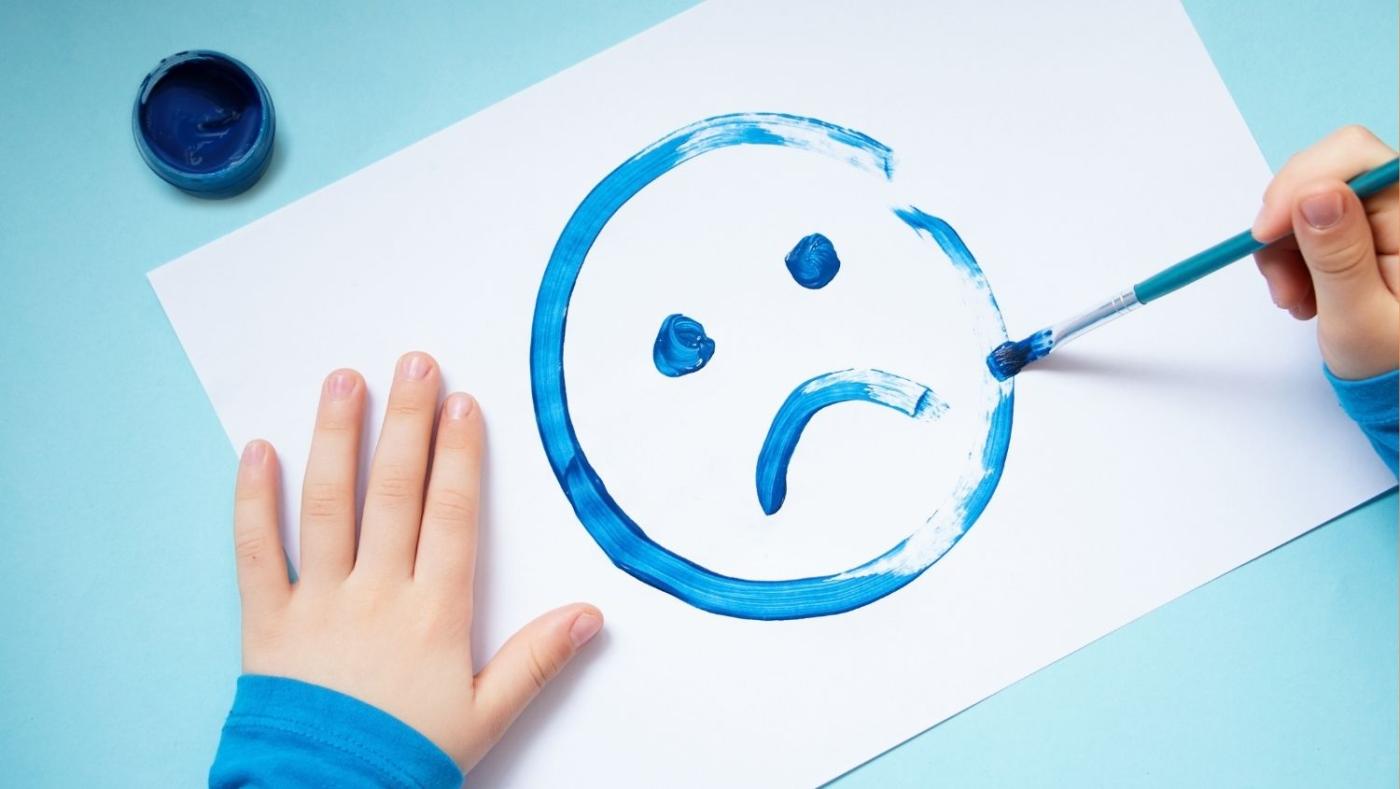 Imagen de una carita triste pintada en acuarela o témpera por un niño.