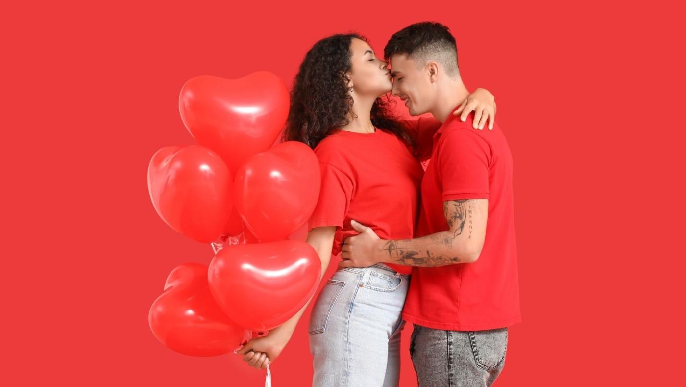 Imagen de una pareja de enamorados con globos en forma de corazón.