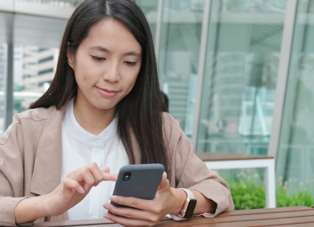 A woman looks at her phone while seated at an outdoor table