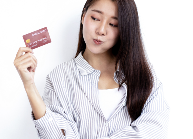 A young woman looks at a credit card that she's holding in her hand