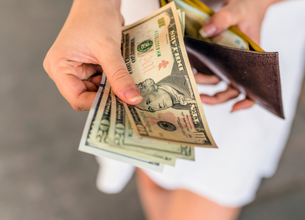 A close-up of a woman's hands holding cash