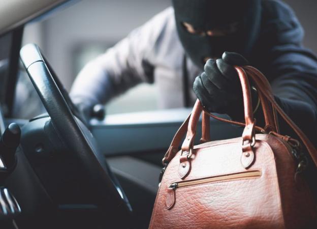 Imagen mostrando una figura enmascarada que sustrae una cartera / bolso de un automóvil. 