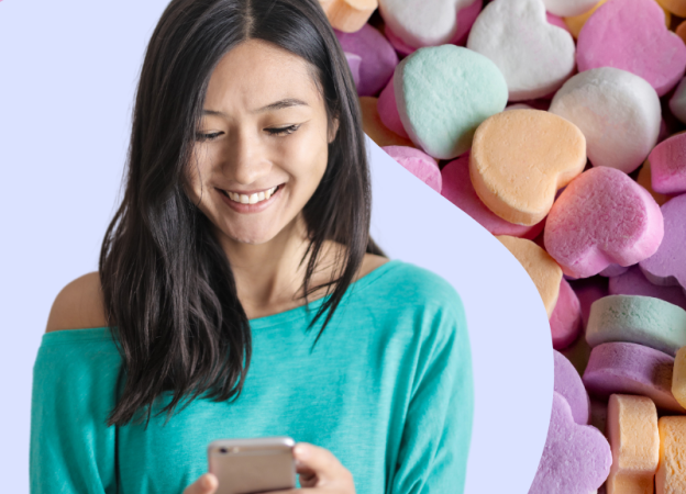 A woman is looking at her phone. Candy hearts are in the background.