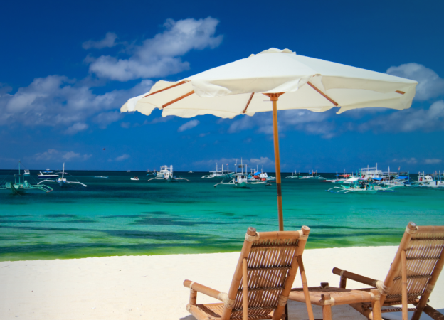 Two beach chairs and a beach umbrella overlook the water on a beach