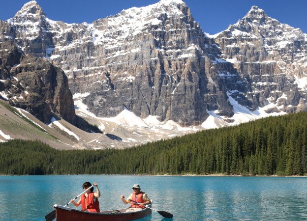 Two people paddle in a canoe at the Canadian Rockies