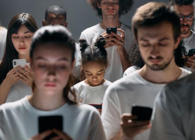 Imagen de personas mirando las pantallas de sus celulares.