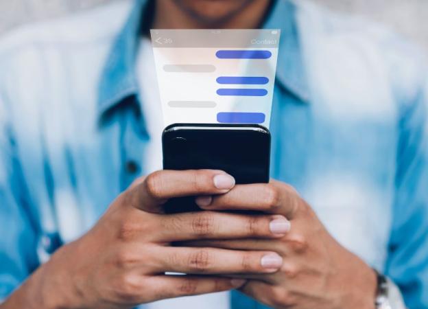 Imagen de una persona mirando la pantalla de su teléfono celular. Superpuesto, se ve el diseño de una app de mensajería.