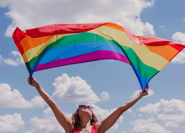 Imagen mostrando una mujer joven que flamea la bandera arcoiris.